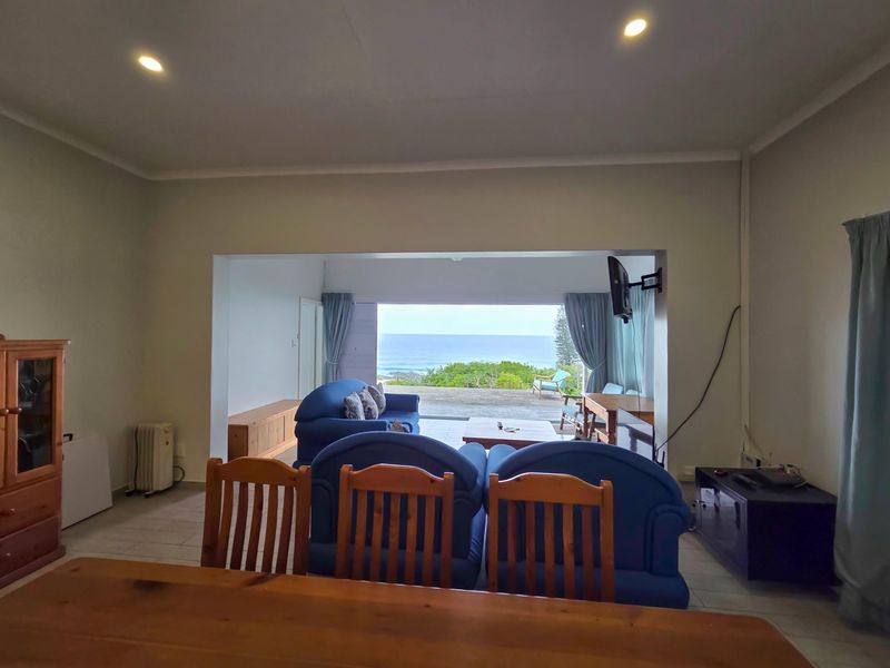 Open plan living area featuring tiled floors, recessed lighting, and large sliding doors opening to a patio with ocean views.