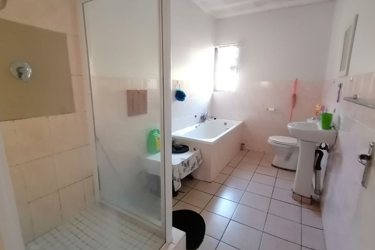 A functional bathroom featuring a separate shower enclosure, a built-in bathtub, and a pedestal sink with tiled flooring and wall finishes.