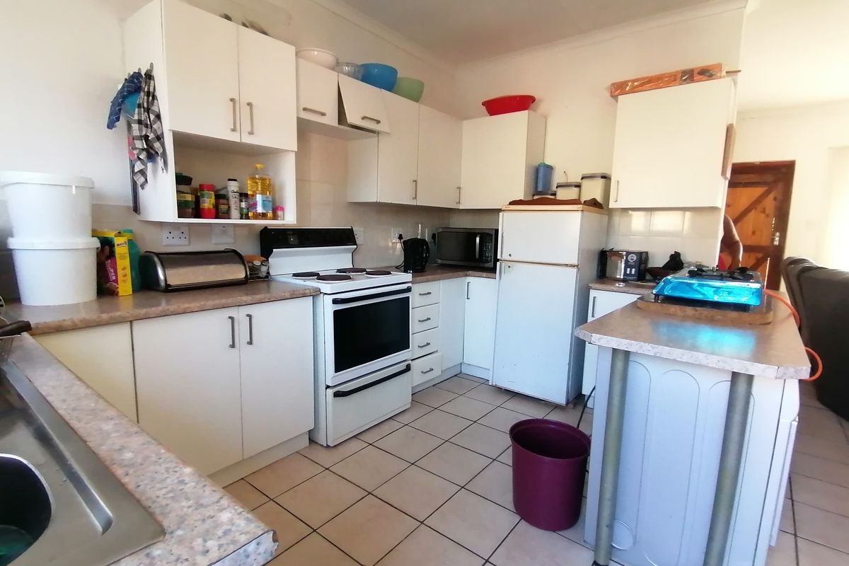 Functional kitchen featuring white cabinetry, laminate countertops, tiled flooring, and a freestanding stove, offering a practical layout for daily meal preparation.