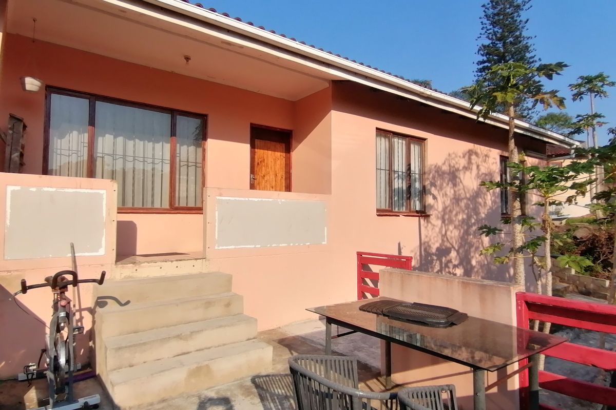 Rear exterior view of the house featuring a paved patio area, concrete steps leading to the entrance, and a tiled roof.