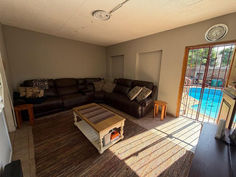 A living room featuring tiled flooring and direct access to an outdoor pool area through a security gate.