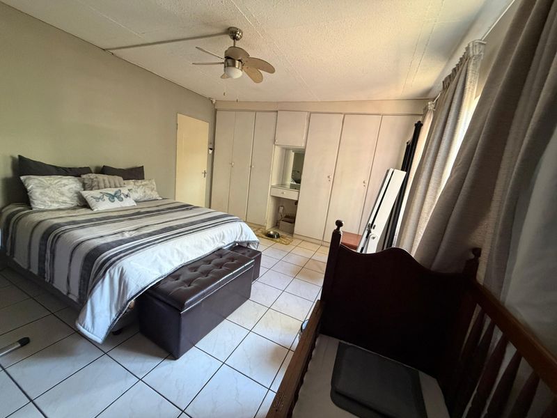 A bedroom featuring built-in floor-to-ceiling cabinetry with a vanity section, tiled flooring, and a ceiling fan.