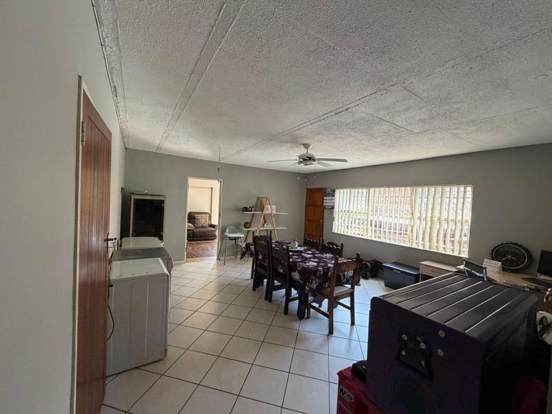 Spacious open-plan living and dining area featuring tiled flooring, a ceiling fan, and large windows allowing for natural light.