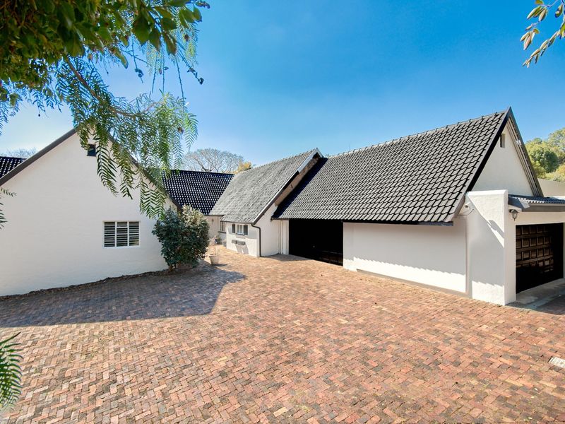 Front elevation of a white masonry house featuring a brick paved driveway and a dark tiled roof with an integrated garage.