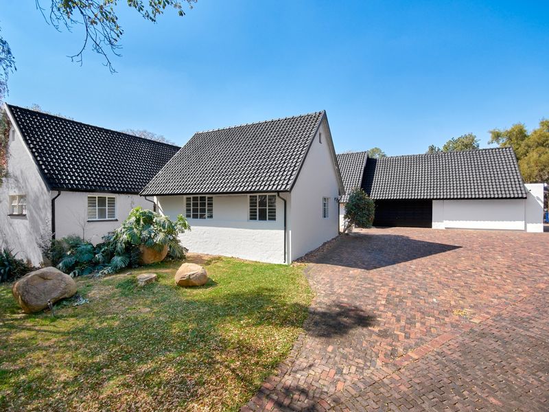 A well-maintained exterior view of the property featuring a brick driveway, white rendered walls, and a dark tiled roof with integrated garage access.
