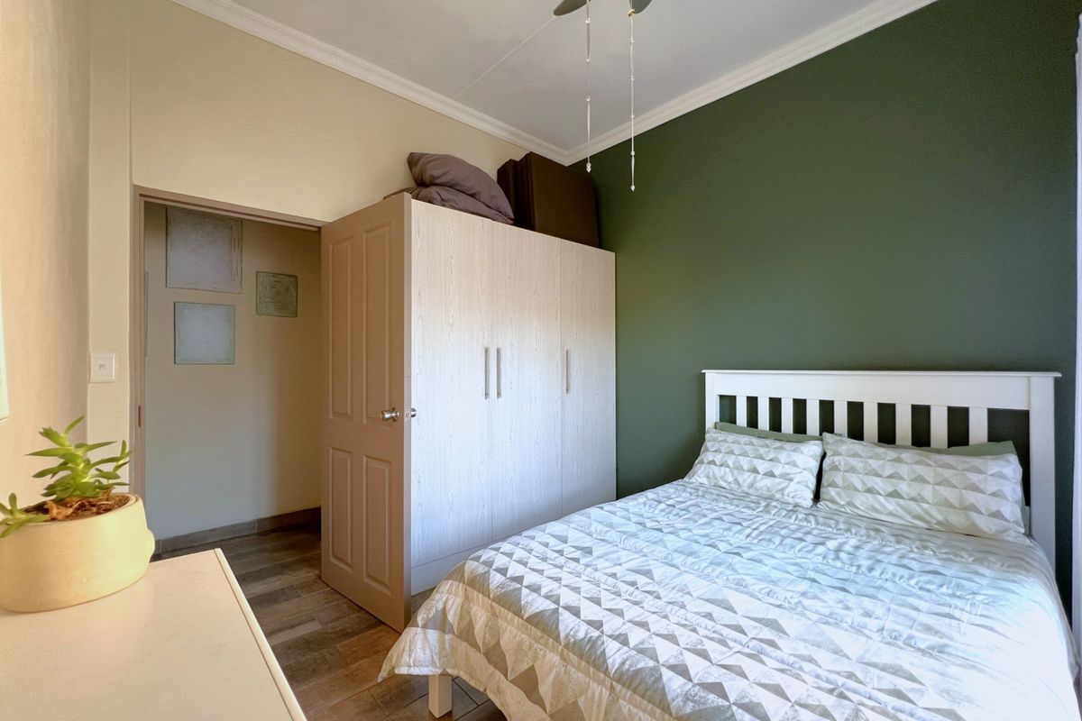 A well-maintained bedroom featuring a built-in wardrobe, ceiling fan, and a feature wall, providing a comfortable and functional living space.