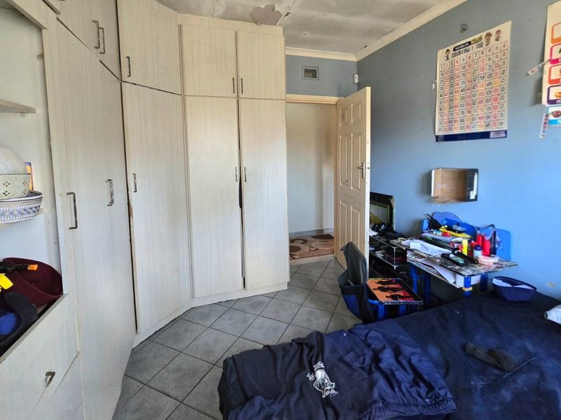 Bedroom featuring built-in cupboards and tiled flooring, requiring ceiling repairs and general cosmetic updates to improve the overall condition.