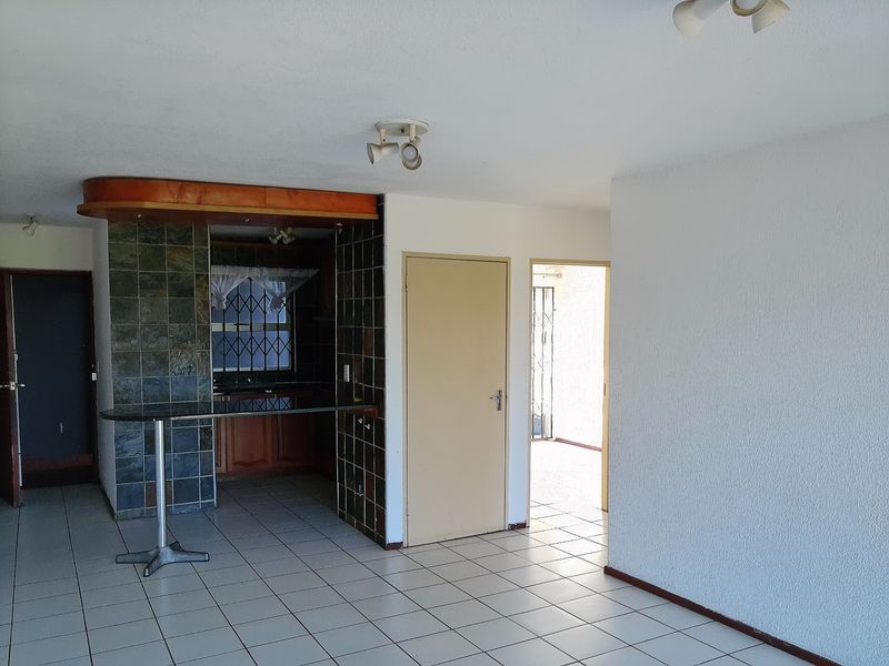 Open plan living area featuring a breakfast bar, tiled flooring, and direct access to adjacent rooms.