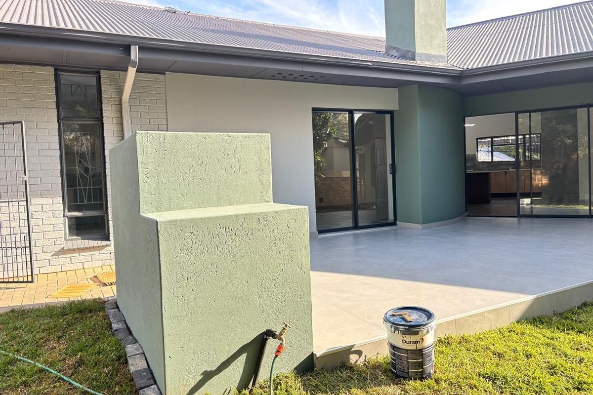 A well-maintained rear patio area featuring tiled flooring, sliding glass doors, and a built-in masonry structure, providing a seamless transition to the garden.