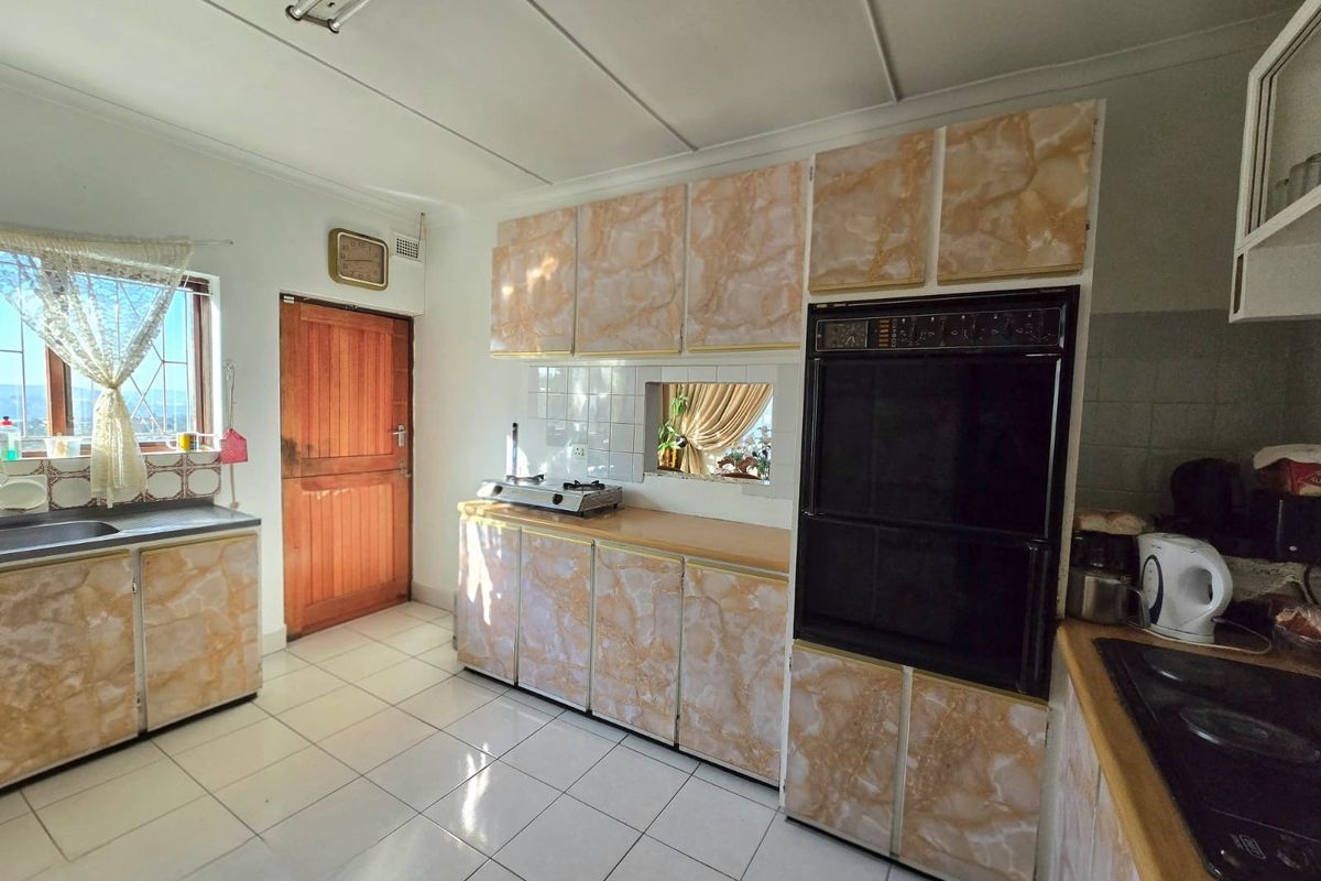 A functional kitchen featuring dated cabinetry, a built-in double wall oven, cooktop, and tiled flooring with a practical layout.