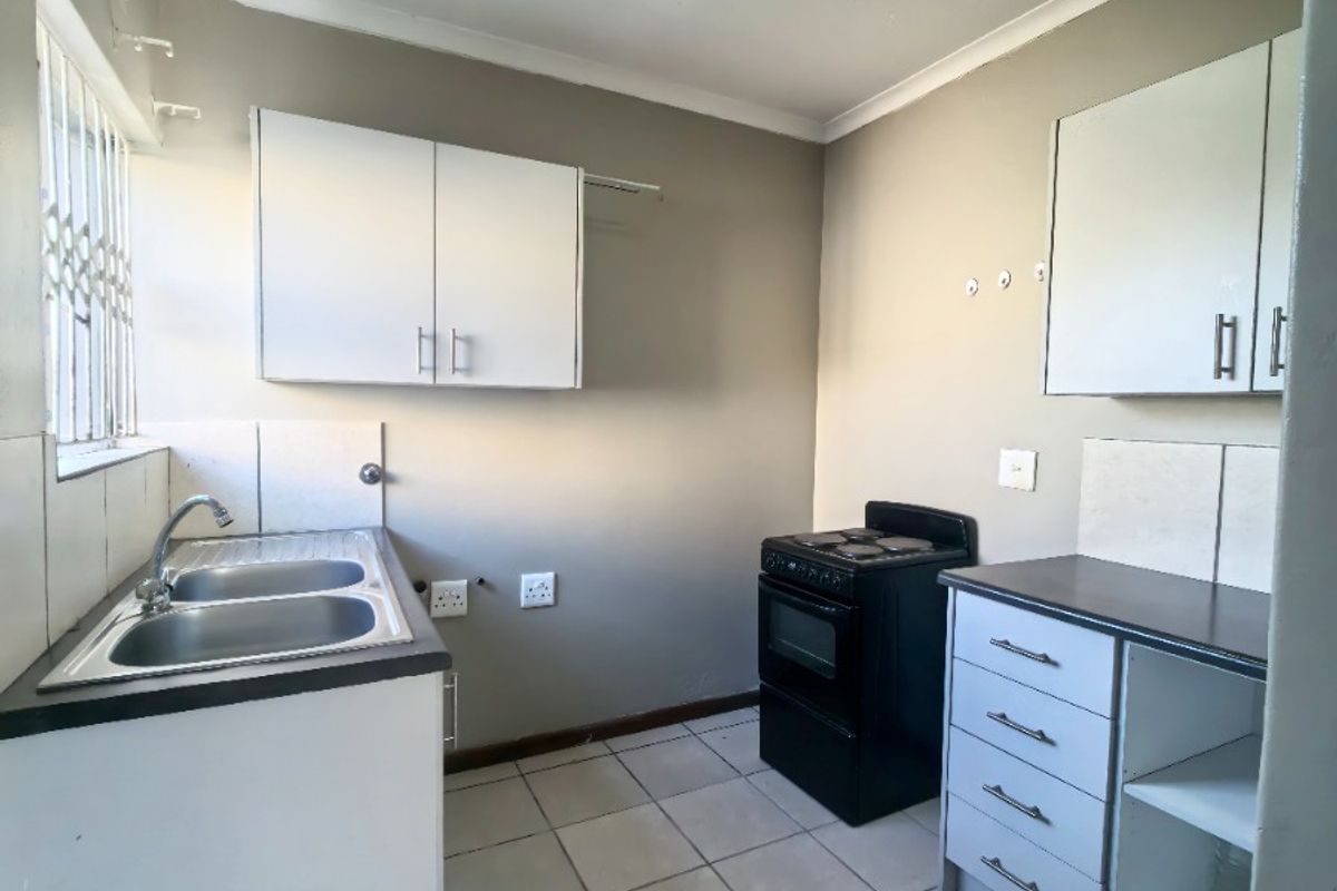 A functional kitchen featuring white cabinetry, a double-basin sink, tiled flooring, and a freestanding stove, offering a practical layout for daily meal preparation.