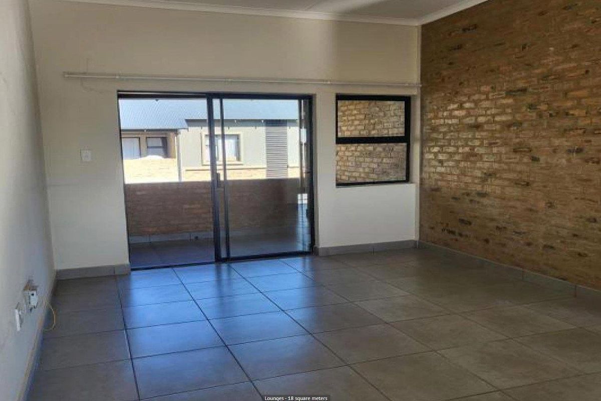 Spacious living area featuring large format floor tiles, a distinctive exposed brick feature wall, and sliding glass doors leading to an outdoor balcony.