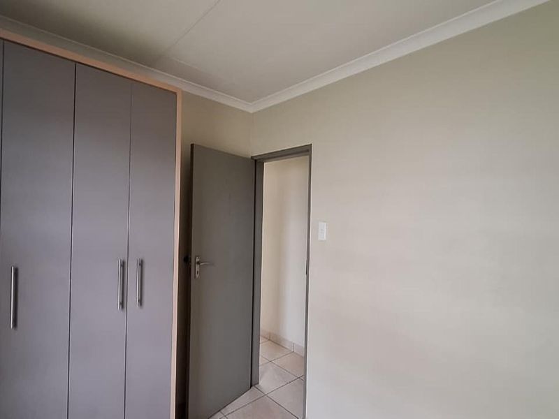 A clean bedroom featuring built-in grey cabinetry and neutral wall finishes, providing a functional and well-maintained living space.