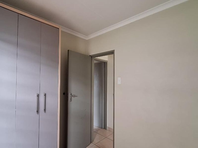 A bedroom featuring built-in cupboards and neutral wall finishes, providing a clean and functional space.