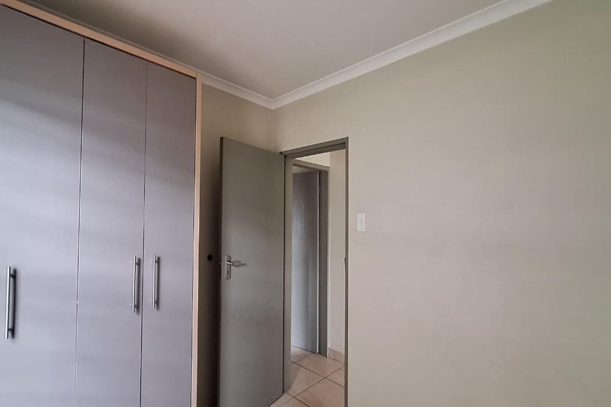 A bedroom featuring built-in cupboards and neutral wall finishes, providing a clean and functional space.