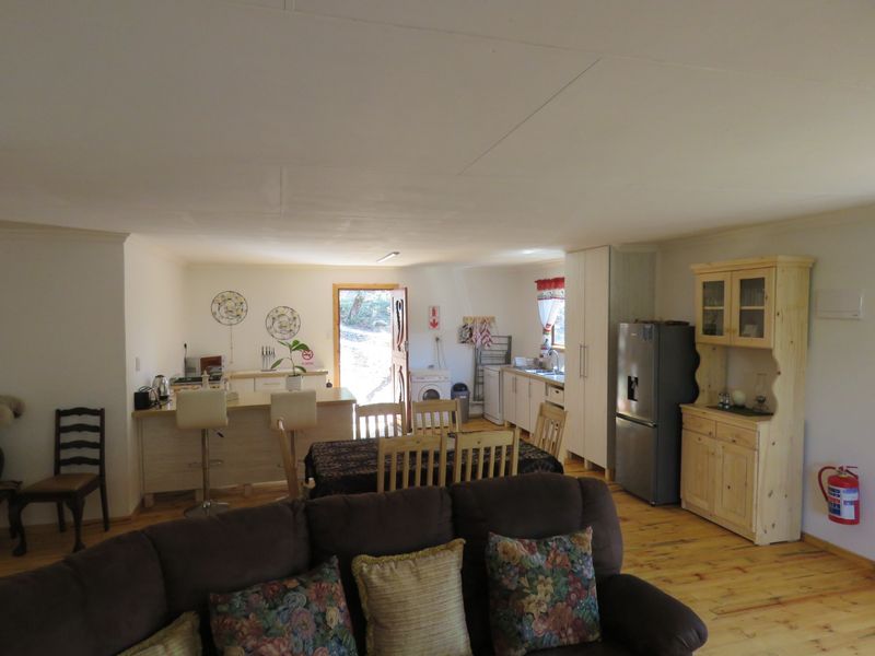 Open plan living and kitchen area featuring timber flooring, breakfast bar, and direct access to the exterior.