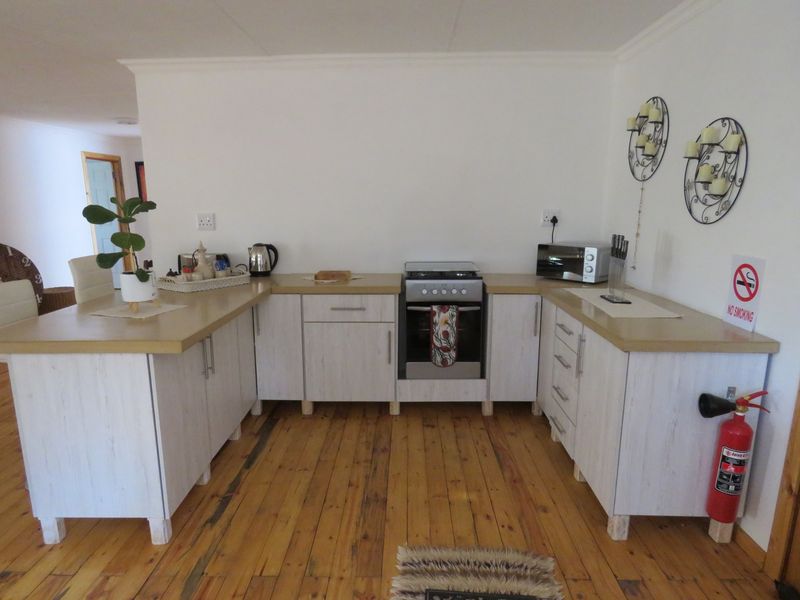 A functional kitchen area featuring light-toned cabinetry, a built-in stove, and exposed timber flooring, offering a practical layout for daily meal preparation.