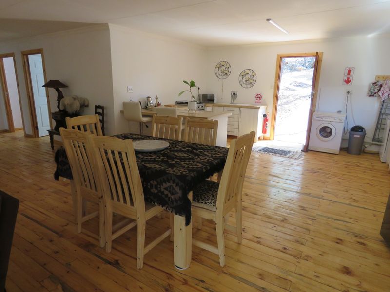 Open plan living and dining area featuring timber flooring, a functional kitchen island, and direct access to the exterior.