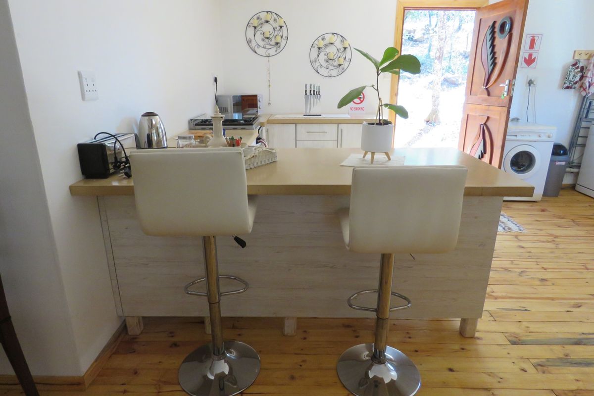 A functional kitchen area featuring a central breakfast bar, wooden flooring, and integrated laundry appliances near the rear entrance.