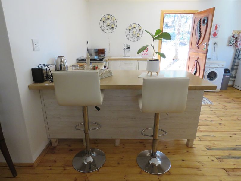 A functional kitchen area featuring a central breakfast bar, wooden flooring, and integrated laundry appliances near the rear entrance.