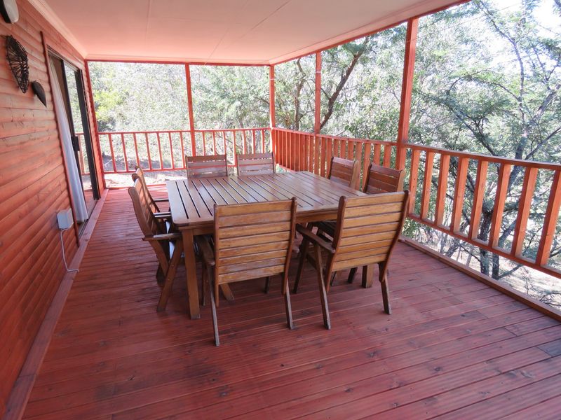 A covered outdoor patio featuring timber decking and a wooden balustrade, offering a spacious area for outdoor dining and relaxation.