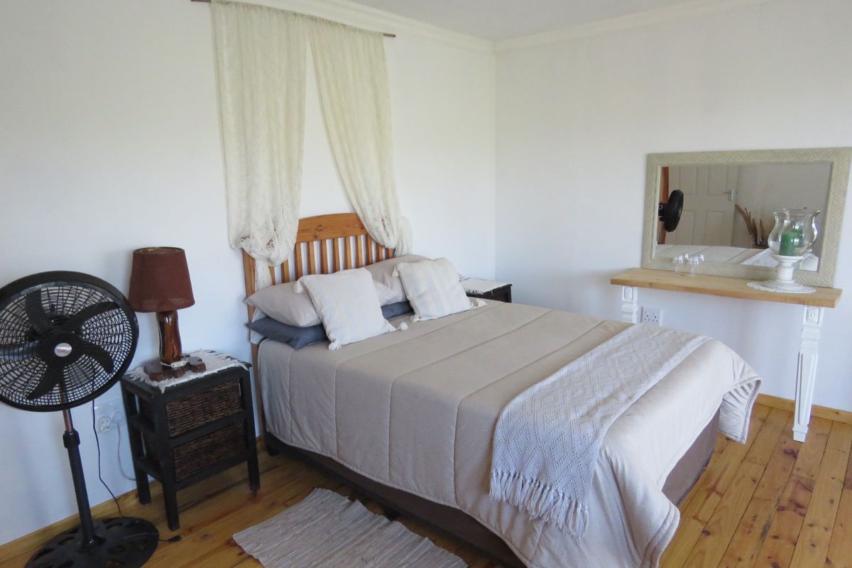 A well-lit bedroom featuring polished timber flooring and a built-in wall-mounted vanity shelf with a mirror.