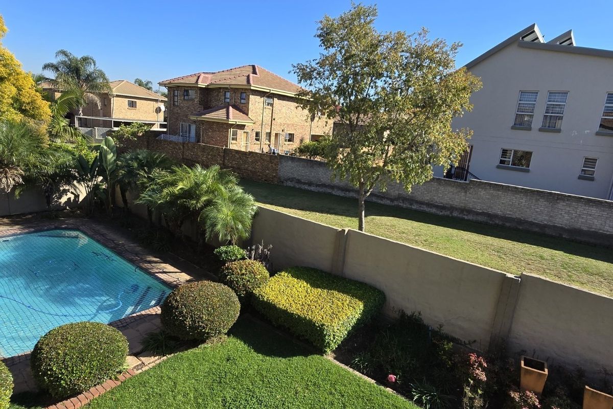 Elevated view of a private backyard featuring a swimming pool, manicured lawn, and perimeter boundary walls.