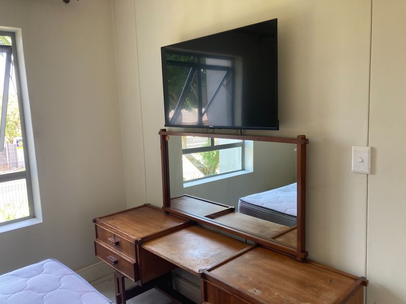 A bedroom featuring casement windows and a wall-mounted television, providing a functional space with natural light.