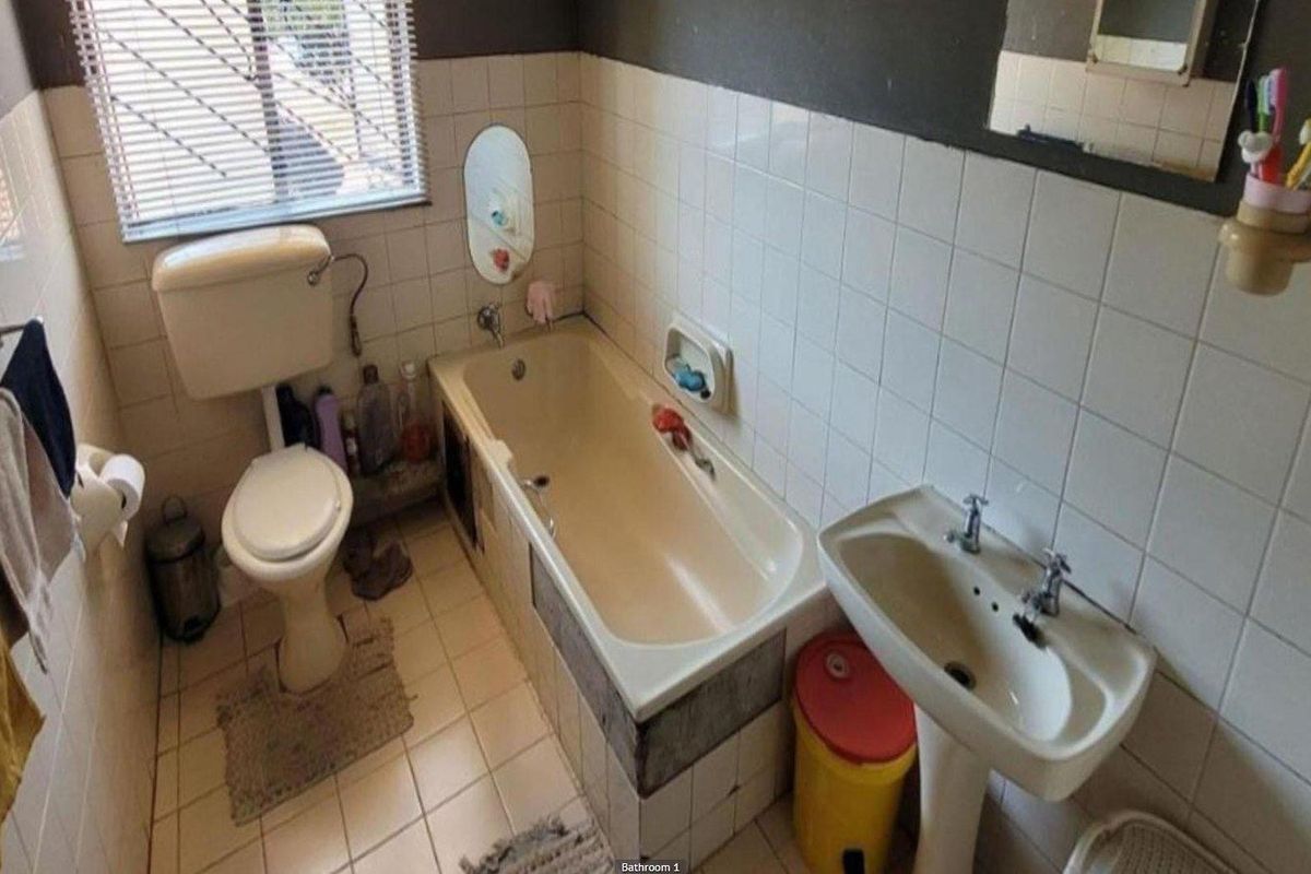A functional bathroom featuring a standard bathtub, pedestal basin, and toilet with tiled walls and flooring.