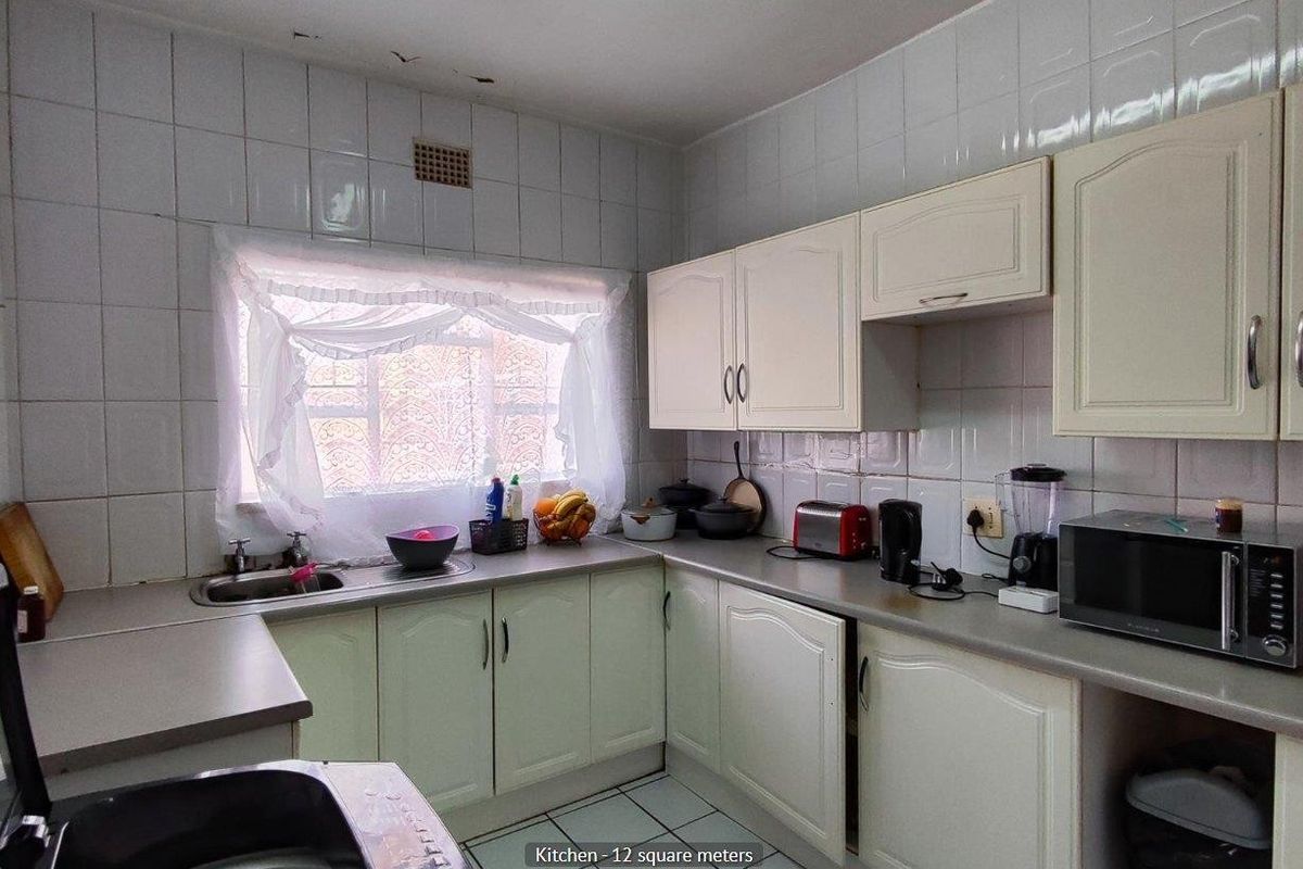 A functional kitchen featuring tiled walls, laminate countertops, and built-in cabinetry, offering a practical layout for daily meal preparation.