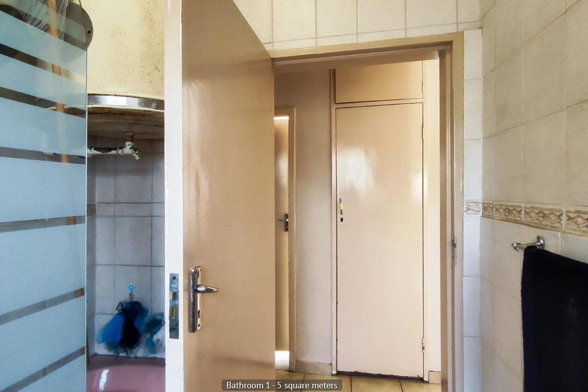 A dated bathroom featuring tiled walls, a built-in water heater, and a standard door entrance, requiring modernization to improve its overall aesthetic and functionality.
