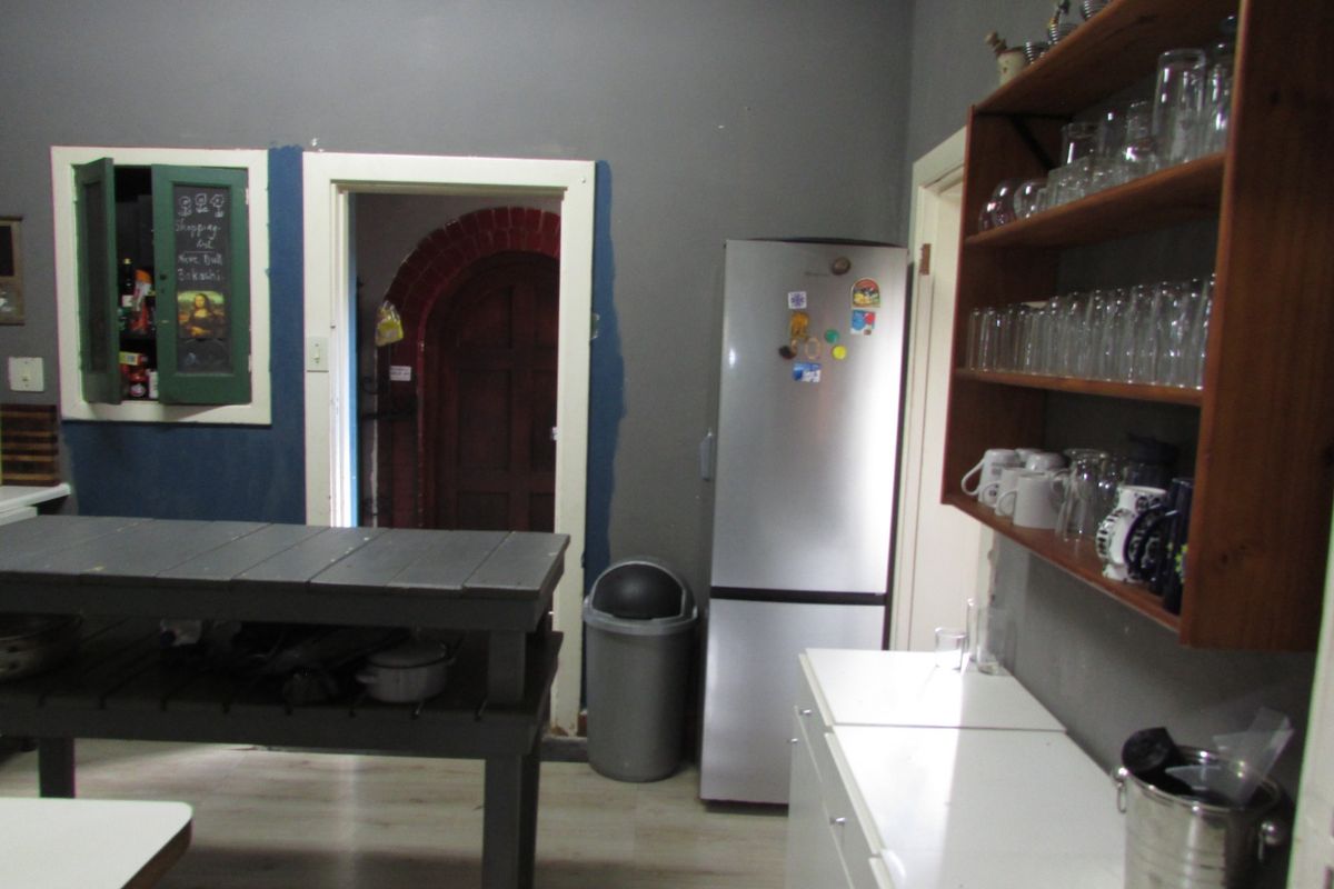 A functional kitchen area featuring built-in cabinetry, open shelving, and a central workspace, with direct access to an arched doorway.