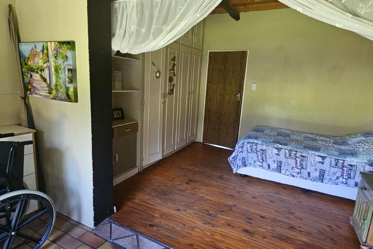 A bedroom featuring built-in wardrobes, wooden flooring, and a raised sleeping area with exposed timber ceiling beams.