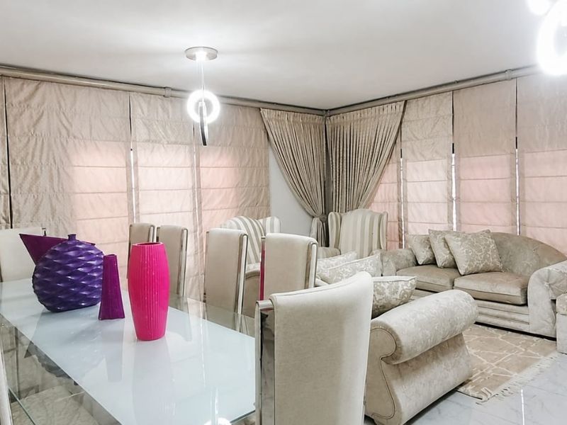 Spacious open-plan living and dining area featuring neutral tiled flooring and extensive window treatments.