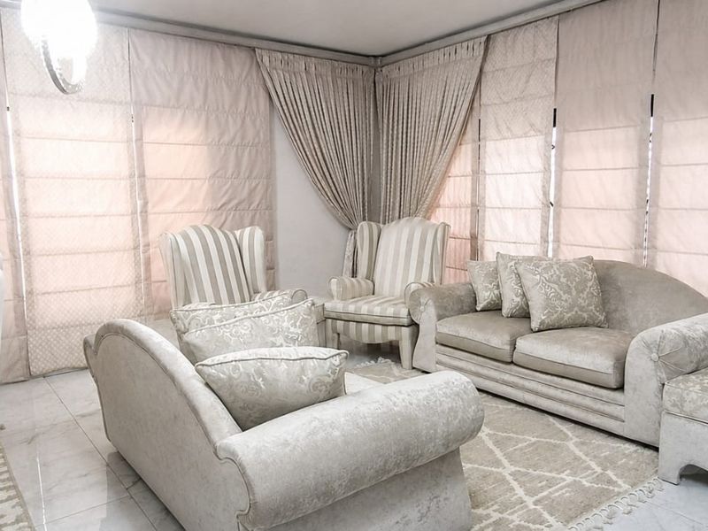 A bright and elegant living room featuring polished marble flooring, a recessed ceiling design, and floor-to-ceiling fitted roman blinds.