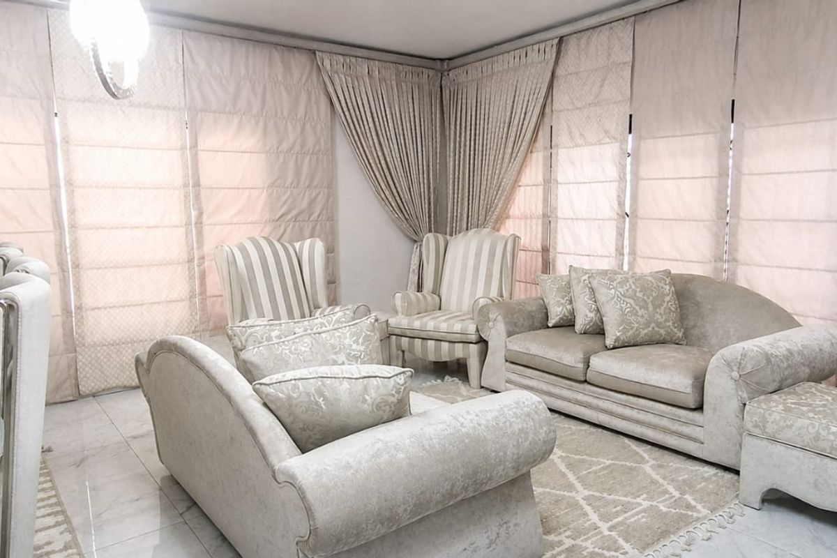 A bright and elegant living room featuring polished marble flooring, a recessed ceiling design, and floor-to-ceiling fitted roman blinds.