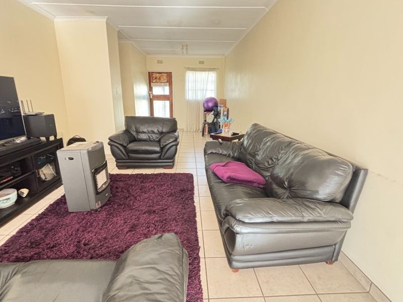 A spacious living room featuring tiled flooring and coved ceilings, offering a blank canvas for potential interior updates and modernization.