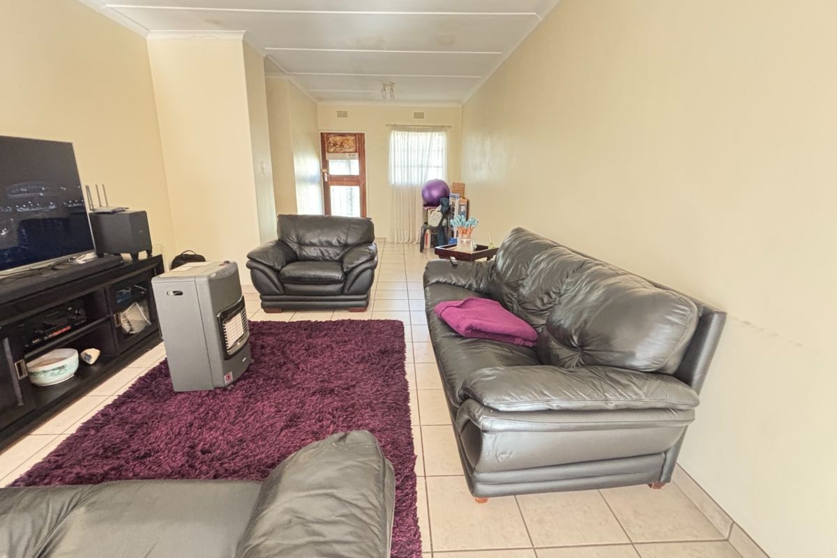 A spacious living room featuring tiled flooring and coved ceilings, offering a blank canvas for potential interior updates and modernization.