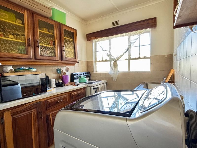 A functional kitchen featuring wooden cabinetry, tiled backsplash, and a freestanding stove, offering potential for a modern renovation.