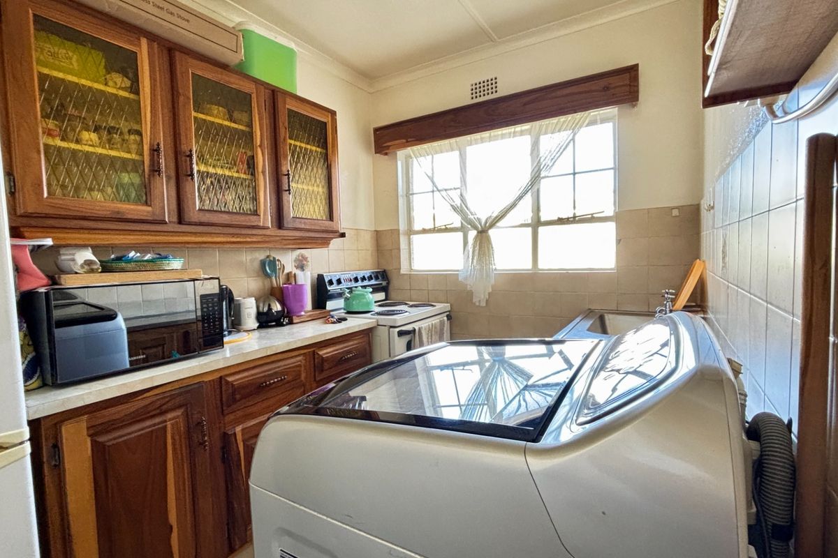 A functional kitchen featuring wooden cabinetry, tiled backsplash, and a freestanding stove, offering potential for a modern renovation.