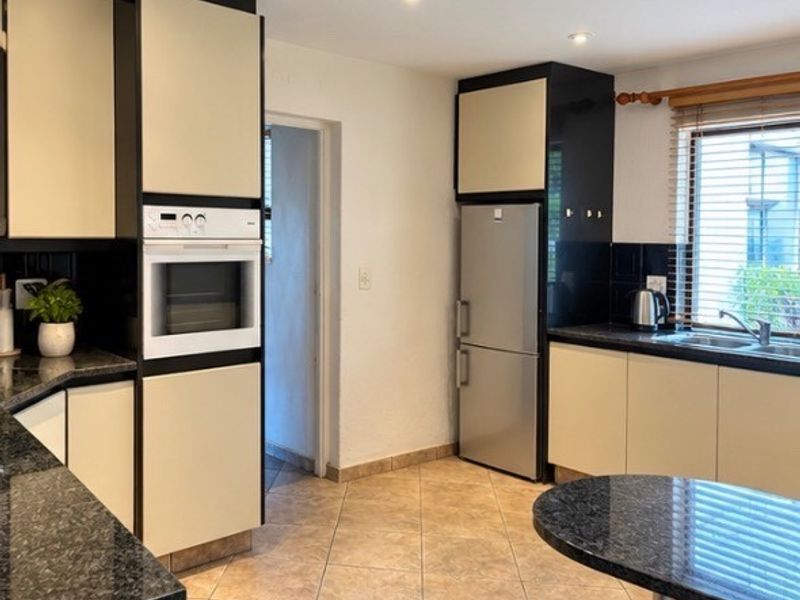 A functional kitchen featuring built-in cabinetry, granite countertops, a built-in oven, and tiled flooring with natural light from the window.