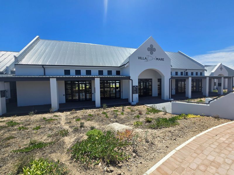 Front elevation of Villa Del Mare featuring a modern architectural design with a metal roof, covered walkways, and glass folding doors.