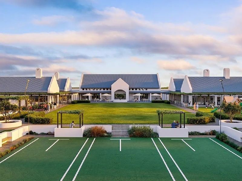 A professional aerial view of a modern clubhouse complex featuring gabled metal roofs, expansive central lawn, and well-maintained outdoor recreational areas.