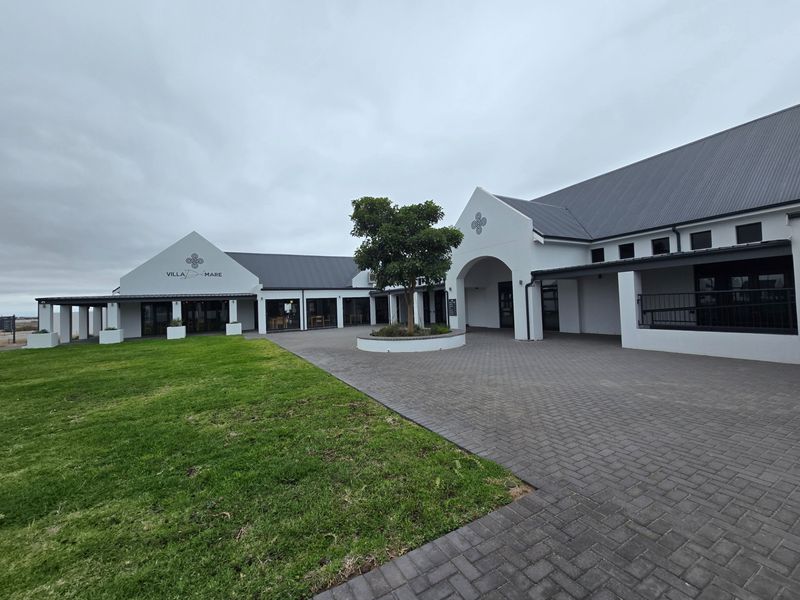 A well-maintained exterior view of the property featuring a paved driveway, landscaped garden, and modern architectural design with a metal roof.