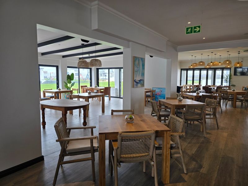 Spacious open-plan dining area featuring laminate flooring, exposed ceiling beams, and large sliding glass doors providing ample natural light and garden access.
