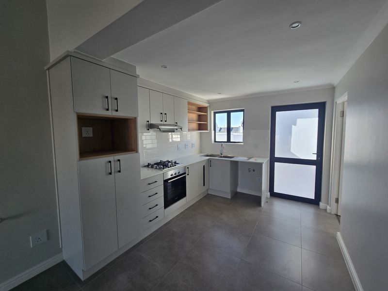 Modern kitchen featuring white cabinetry, gas hob, electric oven, subway tile backsplash, and tiled flooring with direct access to the exterior.