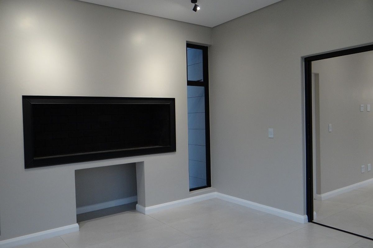 A modern, minimalist living room featuring a sleek built-in fireplace, neutral tiled flooring, and clean architectural lines.