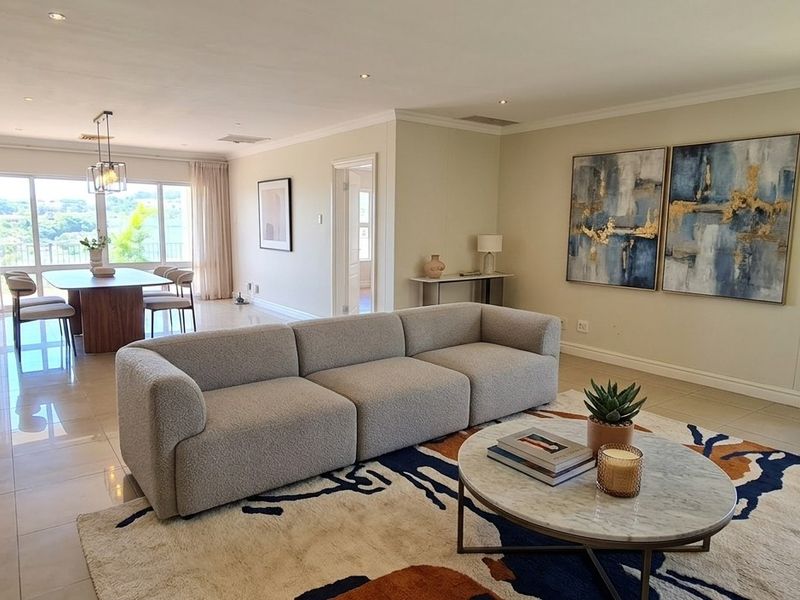 Spacious open-plan living and dining area featuring neutral tiled flooring, recessed lighting, and large sliding doors leading to an outdoor balcony.