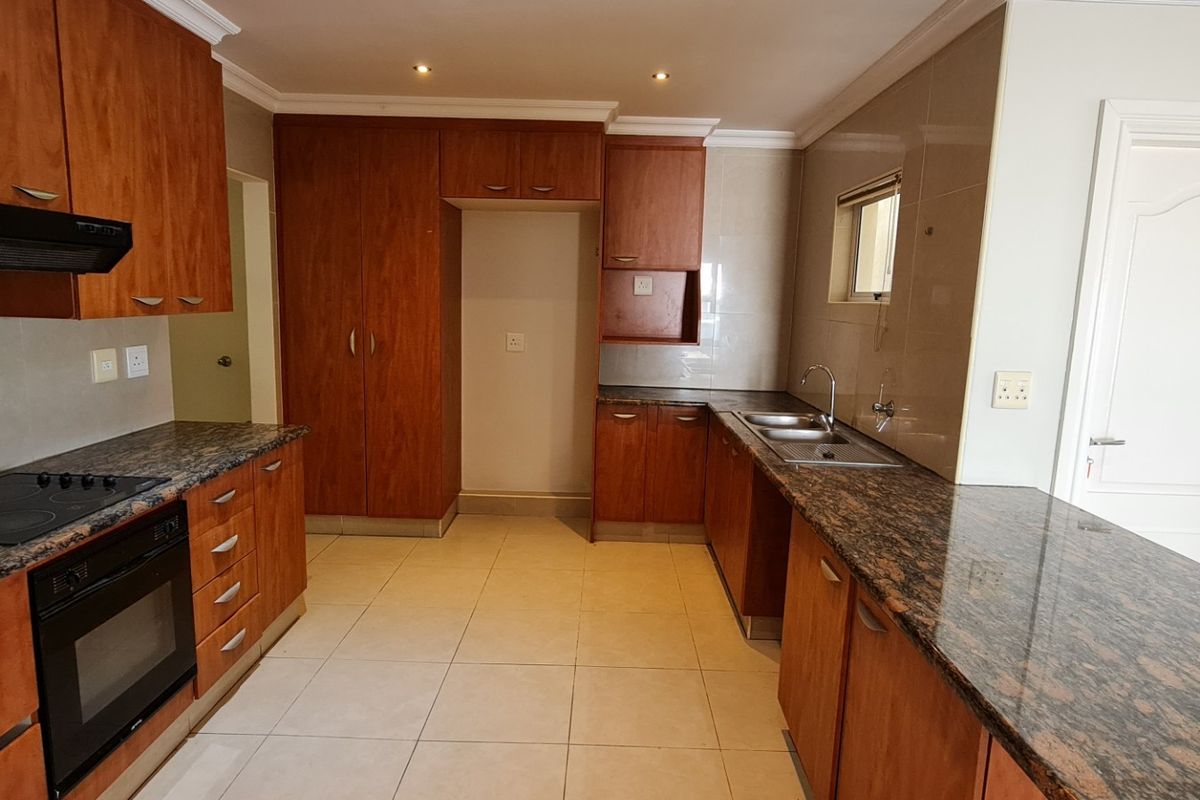 A functional kitchen featuring granite countertops, built-in cabinetry, an electric oven and hob, and tiled flooring.