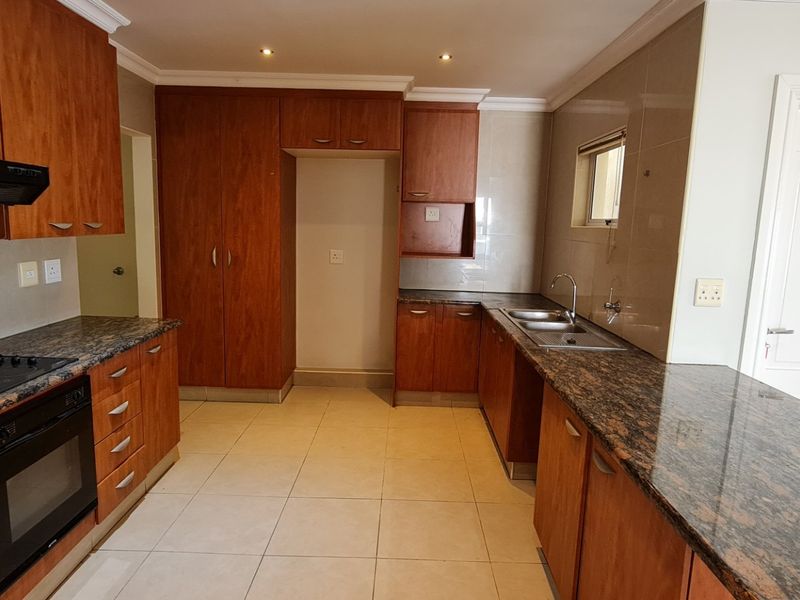 A functional kitchen featuring granite countertops, built-in cabinetry, an electric oven and hob, and tiled flooring.